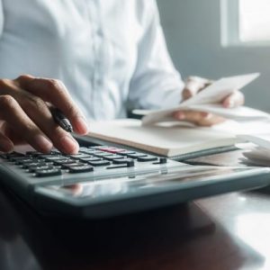 Woman with bills and calculator. Woman using calculator to calculate bills at the table in office. Calculation of costs.